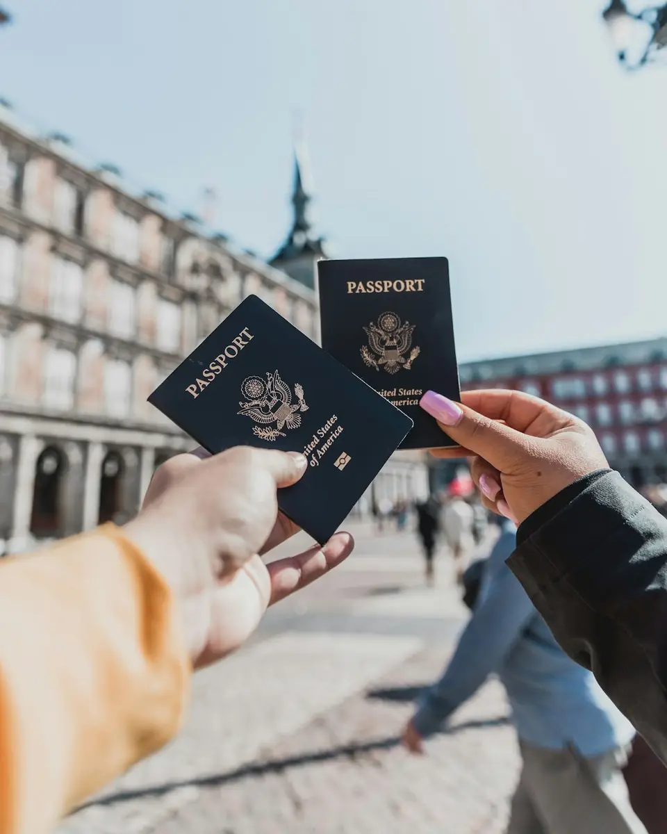 Two people holding passports in a city square